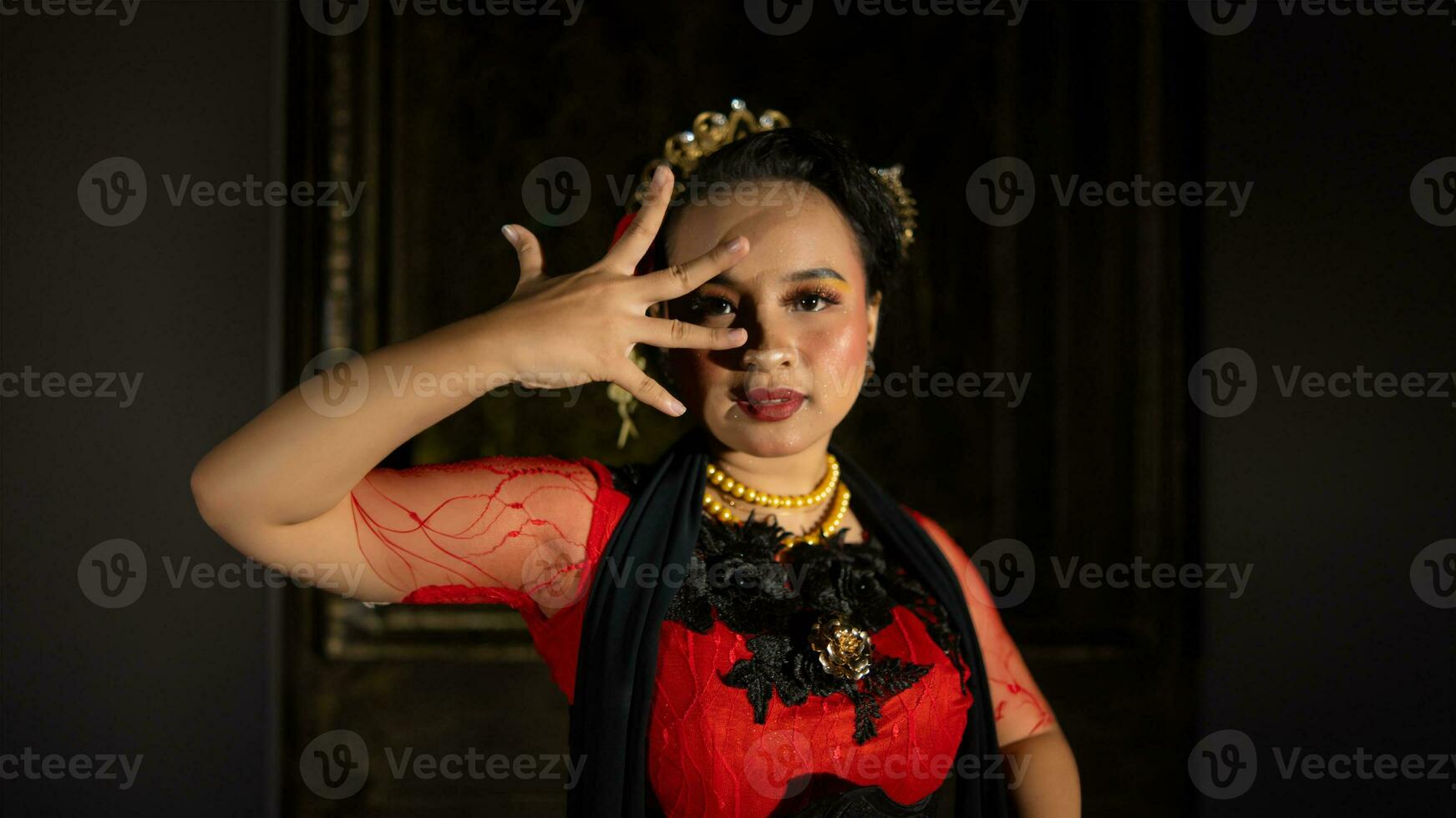 een Indonesisch danser straalt uit charme dat trekt aan de aandacht van de publiek gedurende de prestatie met haar rood jurk foto