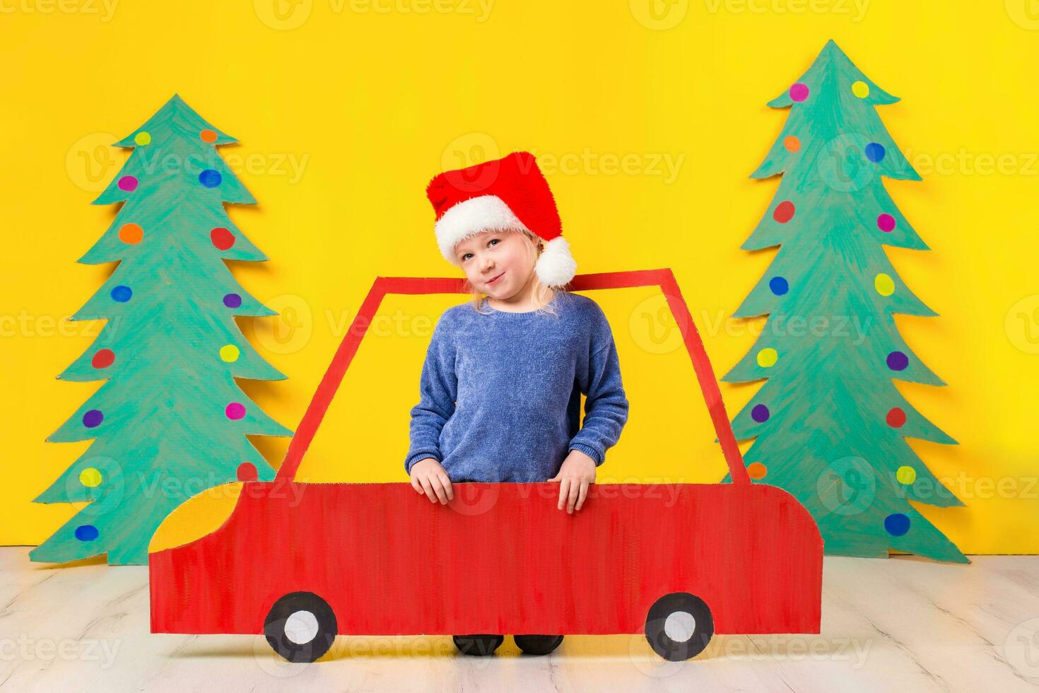 kind met Kerstmis hoed het rijden een auto gemaakt van karton. Kerstmis concept. nieuw jaar vakantie. foto