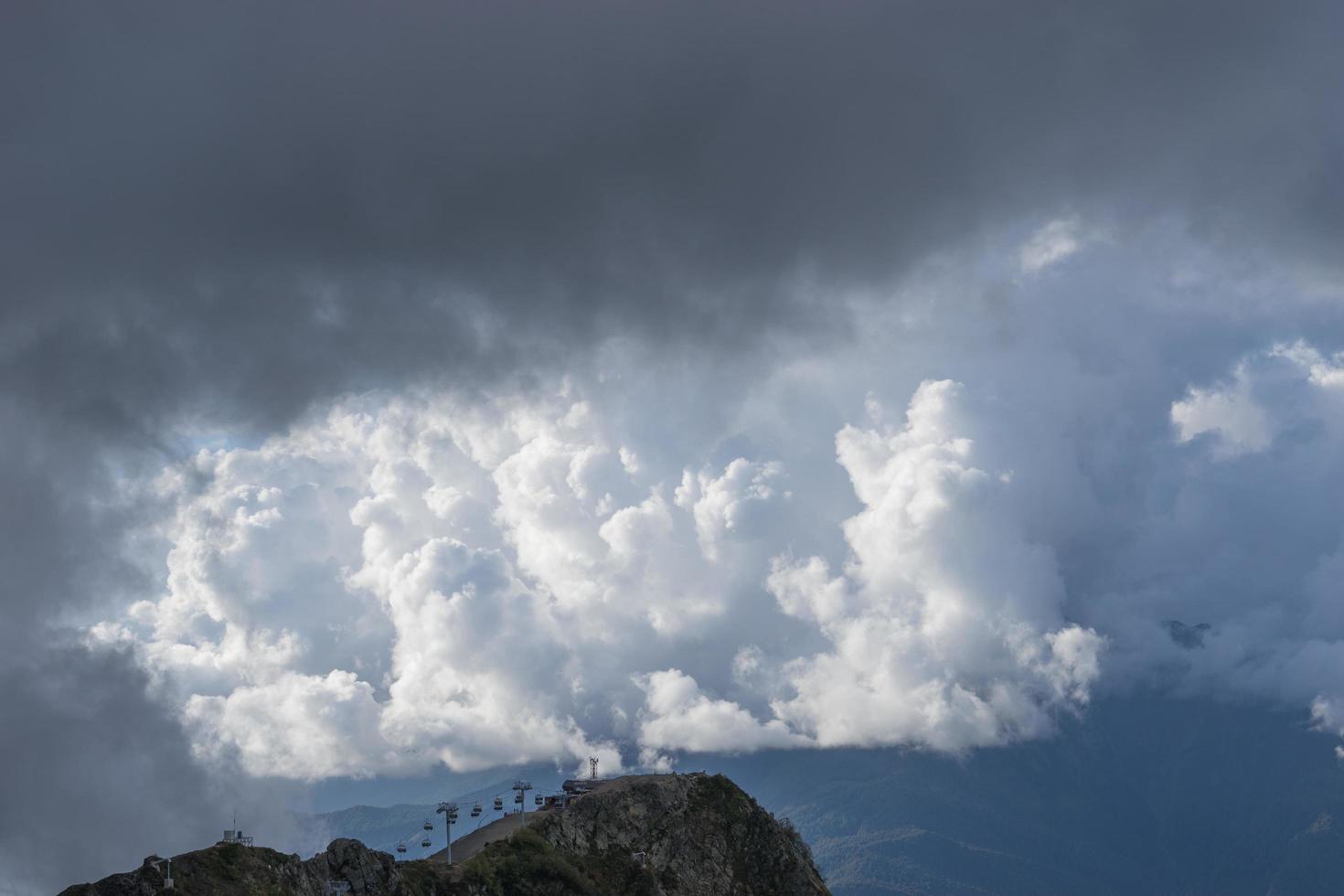 de kabelbaan naar de top van de bergen tegen de pluizige witte wolken foto