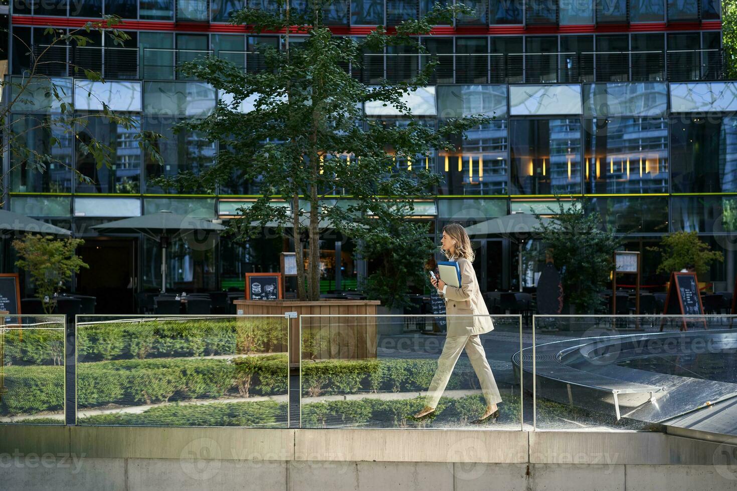 silhouet van jong bedrijf vrouw in beige pak, wandelen in stad centrum, poseren in de buurt kantoor gebouwen, gaan naar werk foto