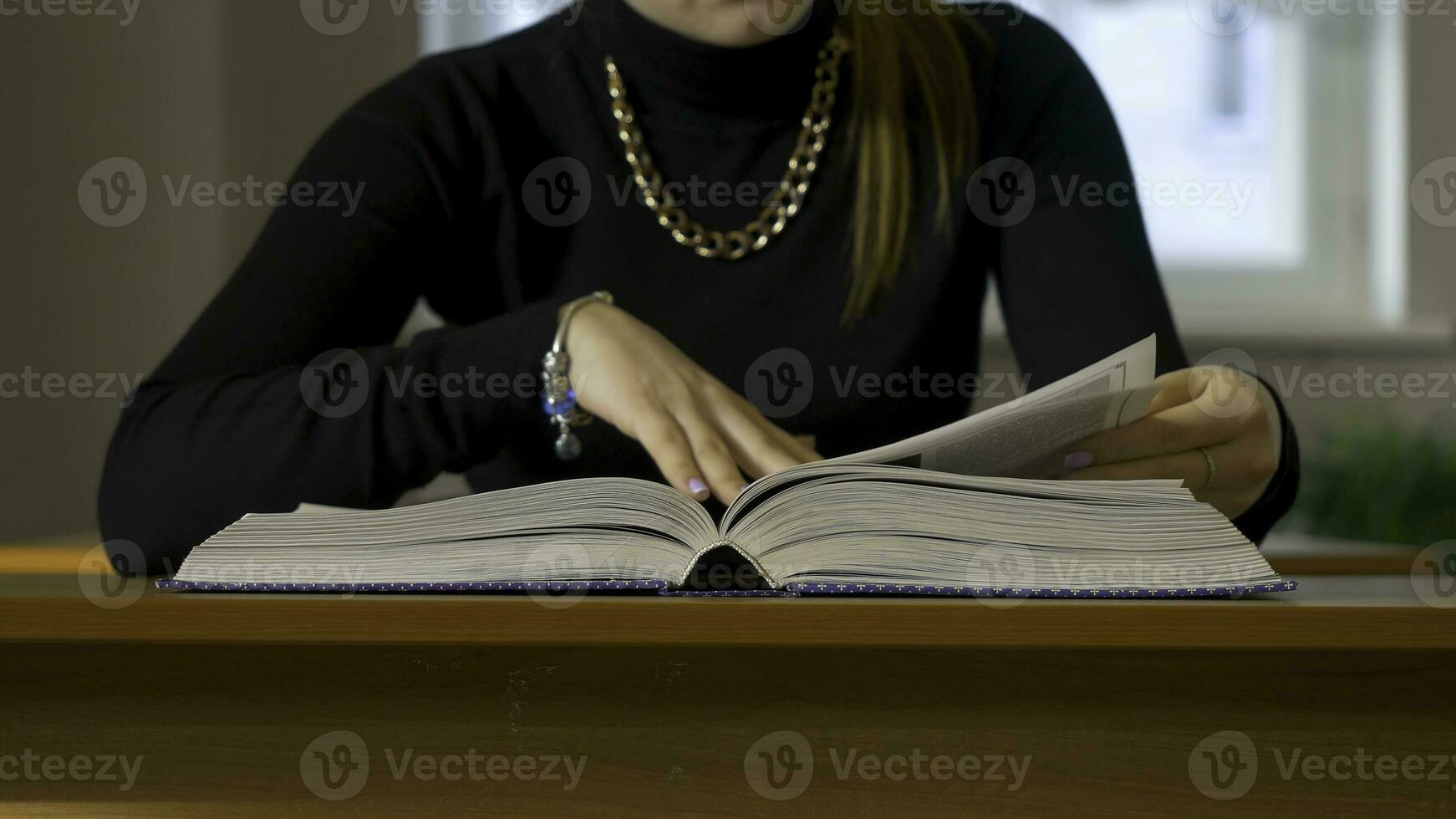 vrouwen handen bladeren door een boek. vrouw zittend Bij de tafel bladeren door de boek foto