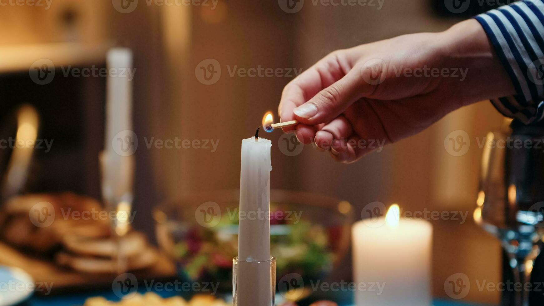 jong vrouw verlichting de kaars aan het wachten haar man voor een romantisch diner. vrouw voorbereidingen treffen feestelijk maaltijd met gezond voedsel voor verjaardag viering, romantisch datum, zittend in de buurt de tafel in keuken. foto