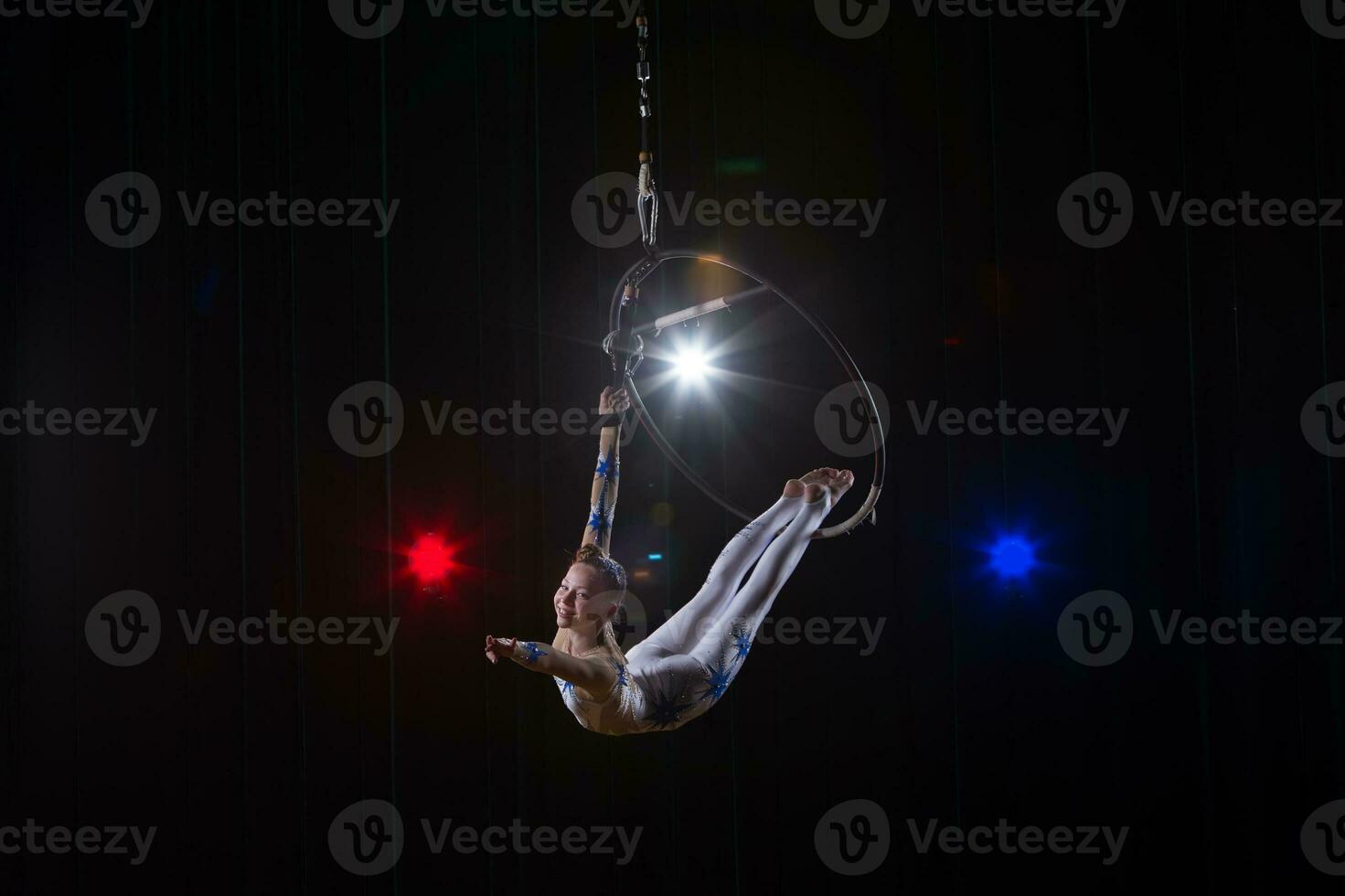 presteert een circus meisje actrice. circus antenne gymnast Aan de hoepel. acrobatiek. tiener presteert een acrobatisch truc in de lucht foto