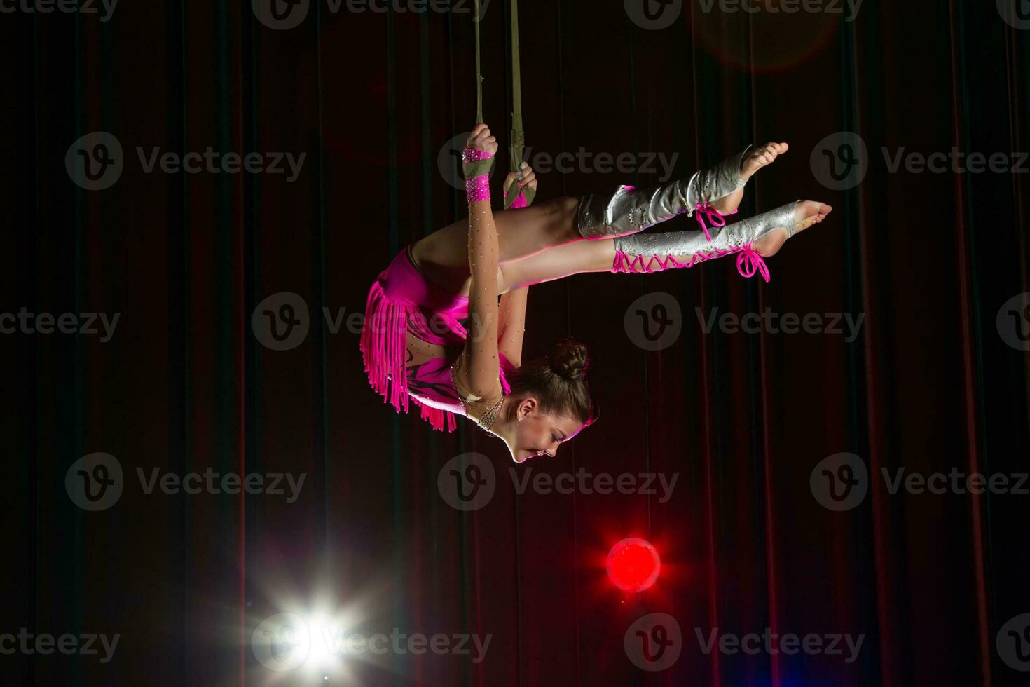 circus artiest acrobaat prestatie. de meisje presteert acrobatisch elementen in de lucht. circus gymnast Aan de stadium foto