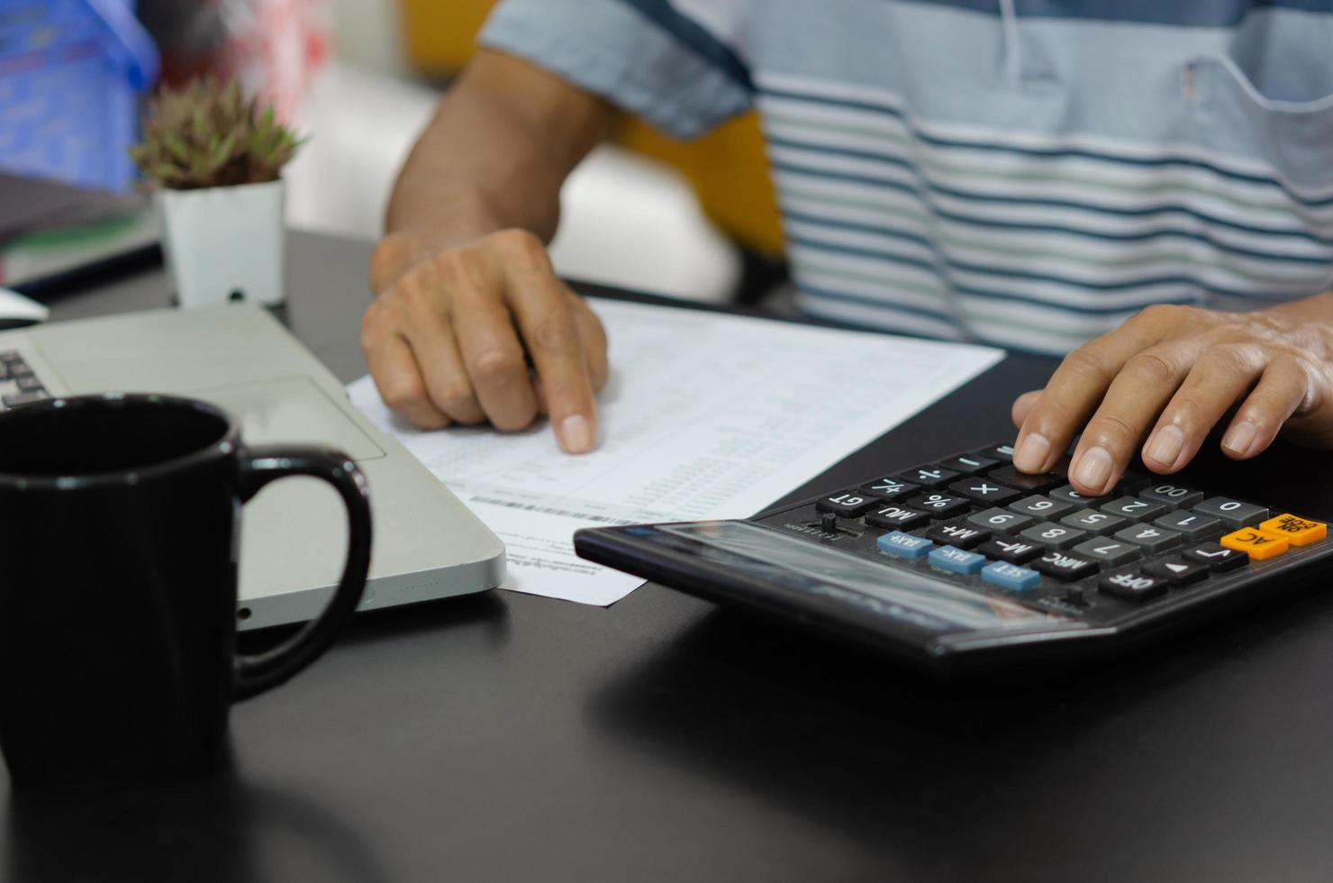 zakenman met behulp van rekenmachine aan een bureau. bedrijfsfinanciën, belasting en investeringsconcepten. foto