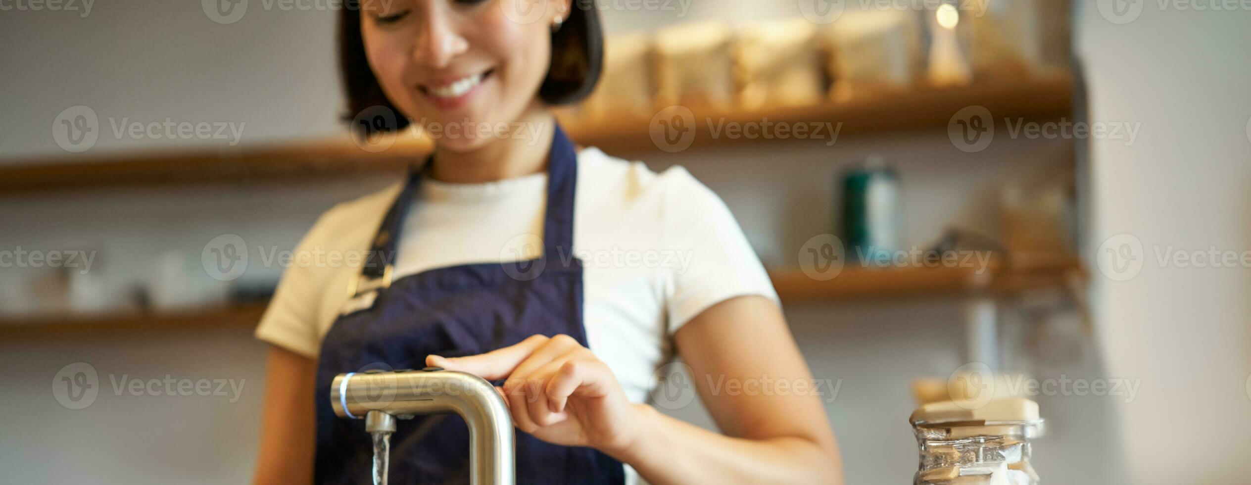 verticaal schot van meisje barista in cafe gieten water van tik, gebruik makend van waterkoker naar brouwen filter koffie foto