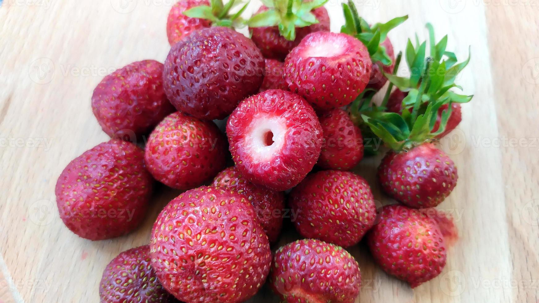 close-up aardbeien met bladeren. rijpe rode bessen liggen in een hoop op tafel. heerlijke aromatische bessen, bovenaanzicht. foto