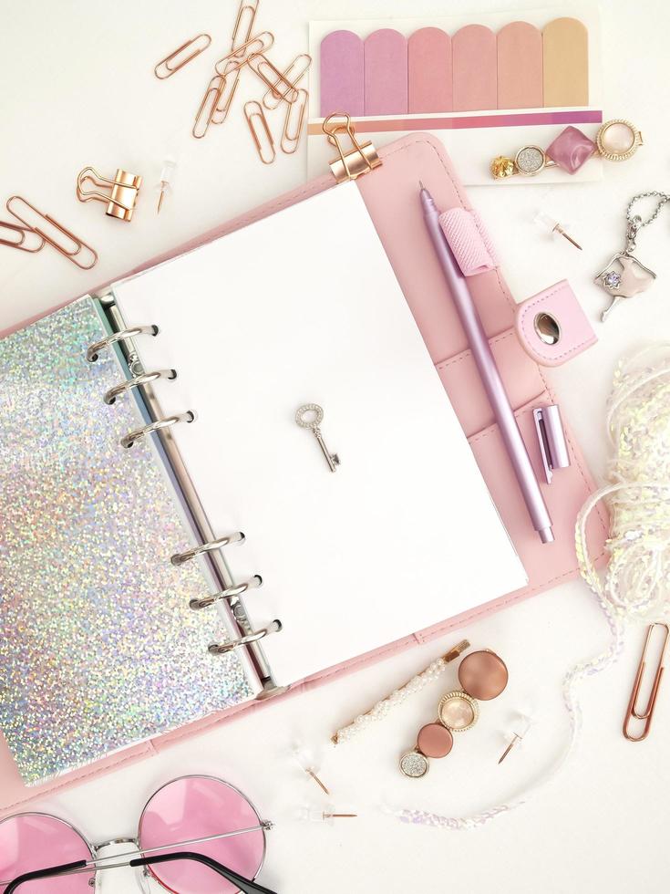 zilveren sleutel op de witte pagina van de planner. dagboek geopend met witte en holografische pagina. roze planner met schattig briefpapier. roze glamour planner decoratie foto