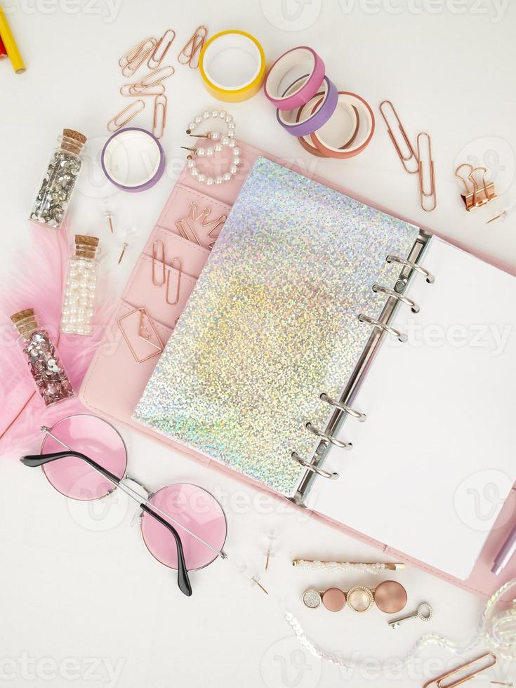 dagboek opent met witte en holografische pagina. roze planner met schattig briefpapier fotograferen in flatlay-stijl. bovenaanzicht van roze planner met zakelijke briefpapier. roze glamour planner decoratie foto