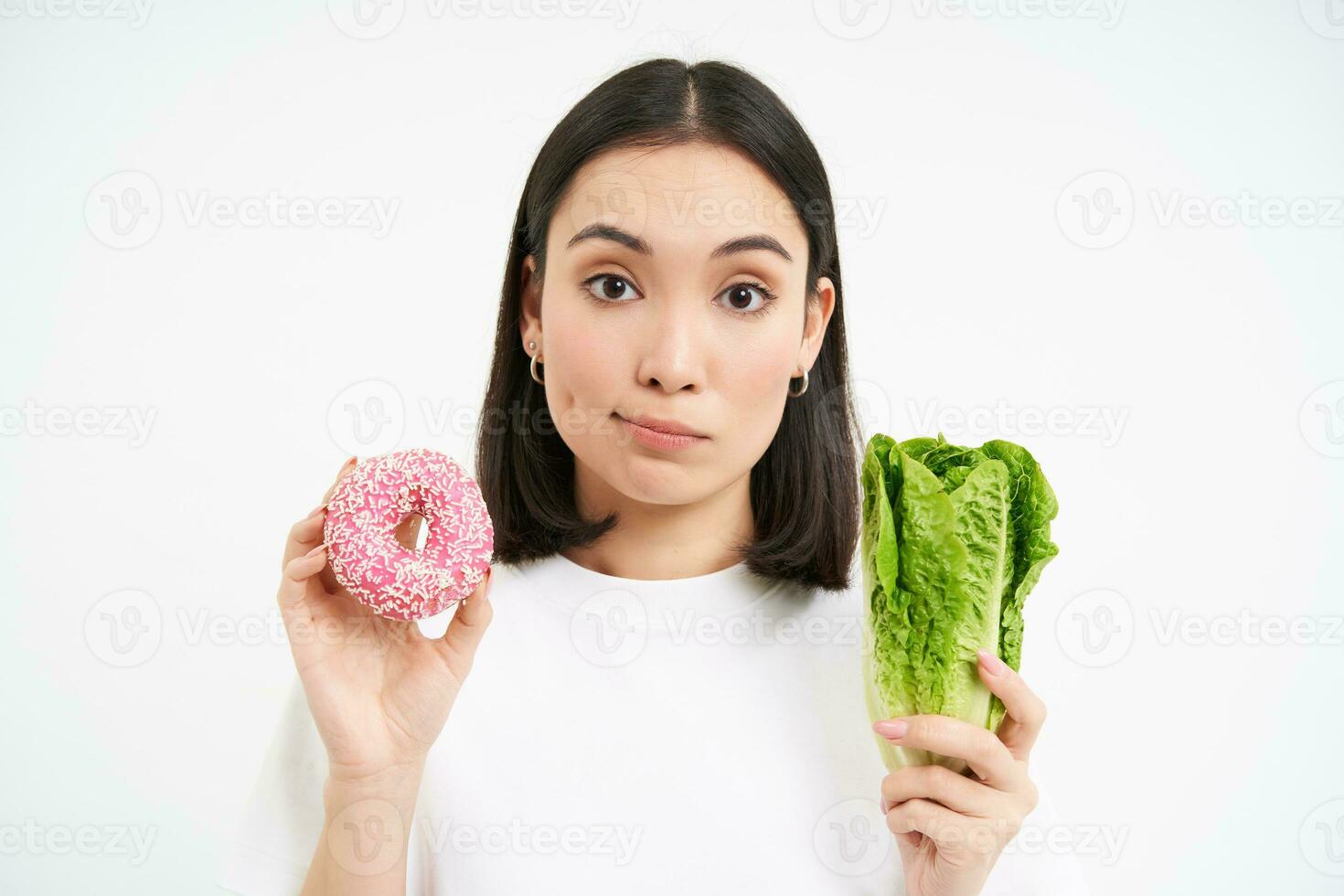 gezond levensstijl concept. gelukkig glimlachen Aziatisch vrouw, tonen een geglazuurd donut en kool, geven keuze, wit achtergrond foto