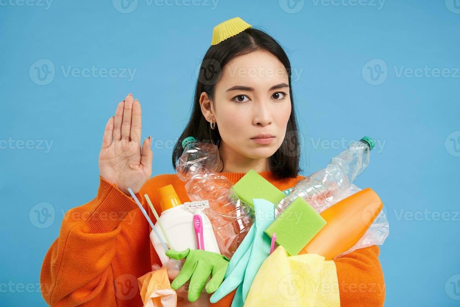 portret van echt Aziatisch vrouw shows hou op teken, houdt plastic voor recyclen, hou op het werpen verspilling in algemeen bak, blauw achtergrond foto