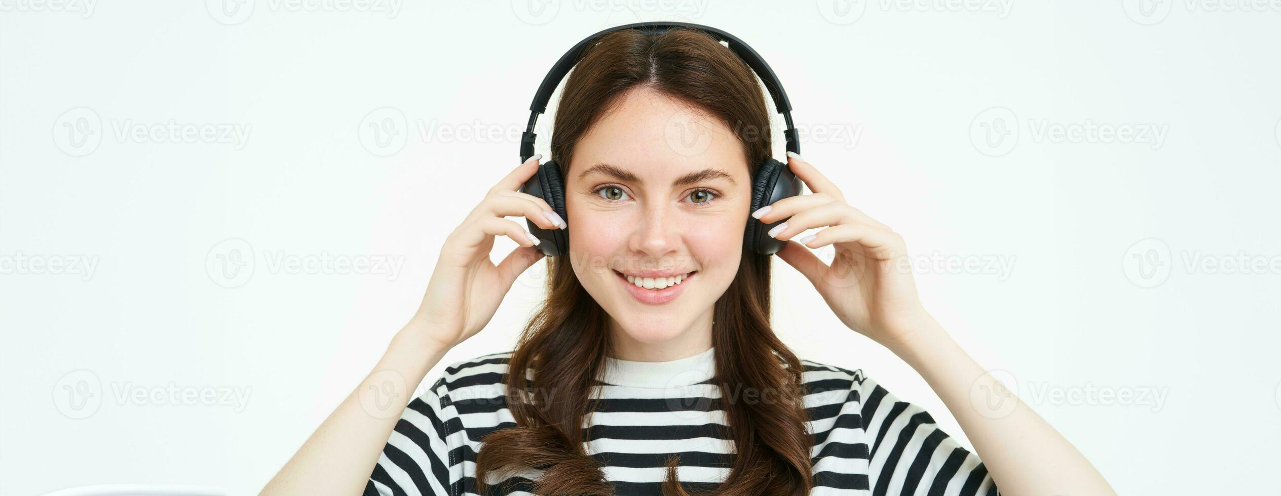 portret van vrouw, lachend, vervelend draadloze koptelefoon, luisteren muziek, aan het studeren in oortelefoons, staand geïsoleerd over- wit achtergrond foto