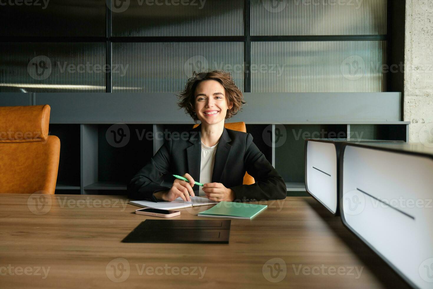 jong zakenvrouw aan het wachten voor begin van ontmoeting. zakelijke vrouw in pak zittend in kantoor, werken Aan documenten, aan het wachten voor cliënt foto