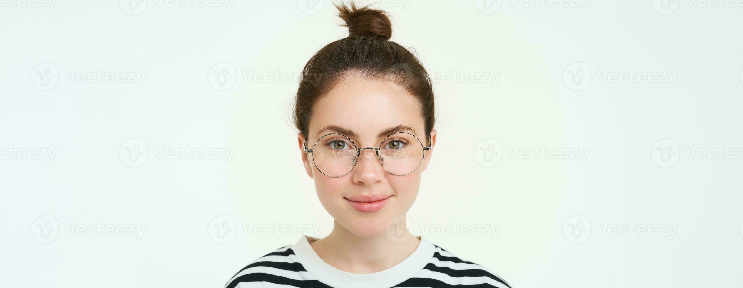 portret van mooi jong vrouw in bril, vervelend brillen, glimlachen en op zoek Vrolijk, proberen Aan nieuw bril, staand over- wit achtergrond foto