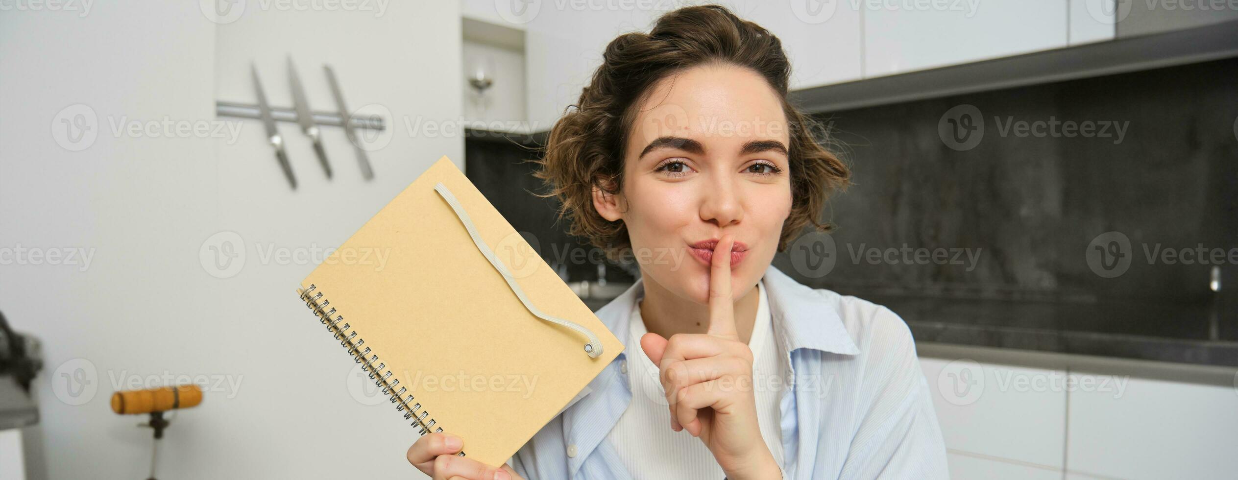 jong vrouw houdt haar dagboek, shows geheim, stil gebaar, persen vinger naar lippen, zet haar gedachten in schrijven foto