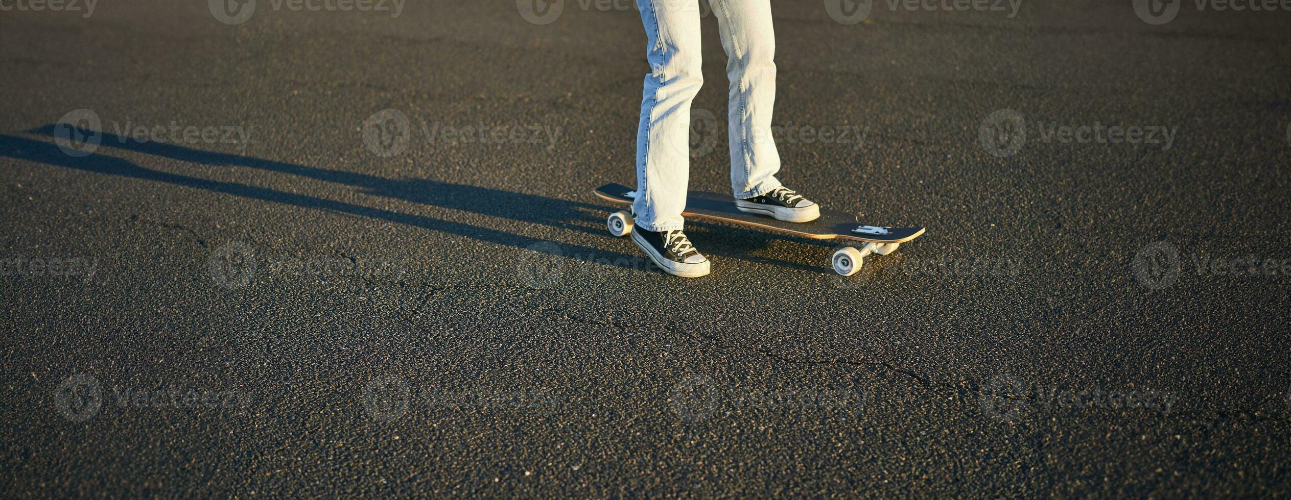 bijgesneden schot van poten Aan longboard. schaatser meisje rijden haar skateboard Aan straat. vrouw tiener Aan kruiser foto