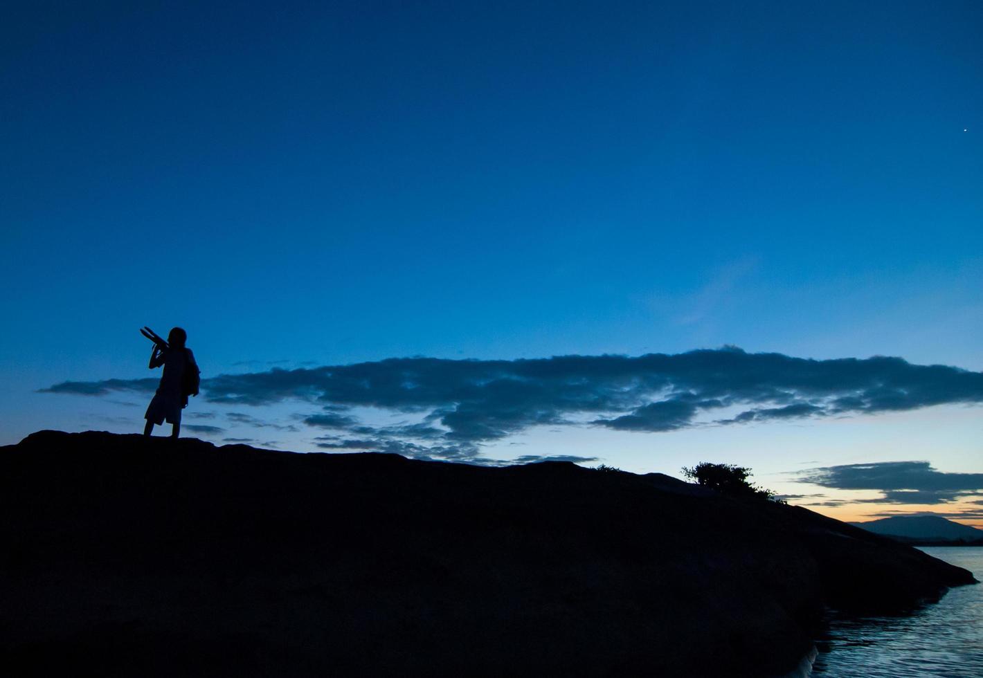 silhouet van fotograaf die een landschapsfoto maakt tijdens zonsopgang foto