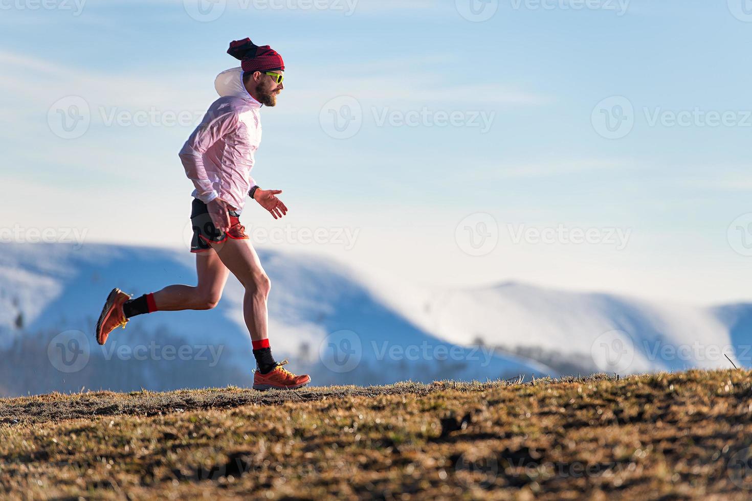 berg race. training van een atleet tussen weilanden en sneeuw foto