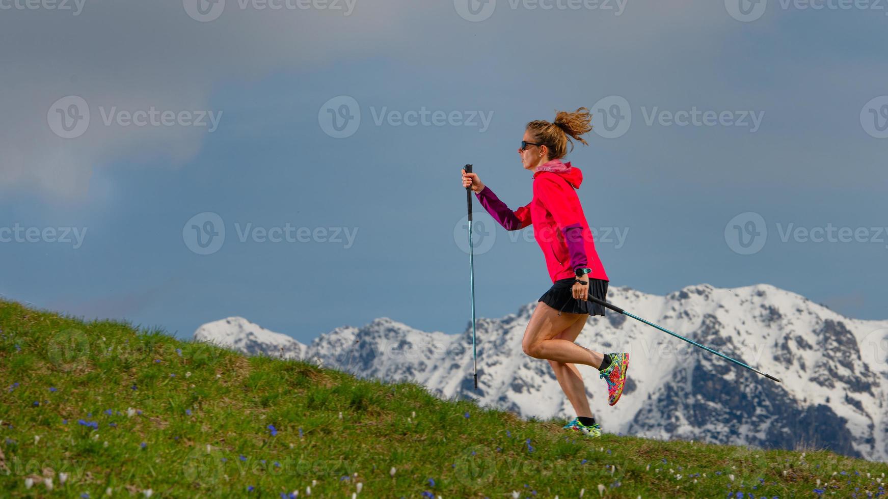 nordic walking en trailrunning een meisje met stokken op lentebrasem met besneeuwde achtergrond foto