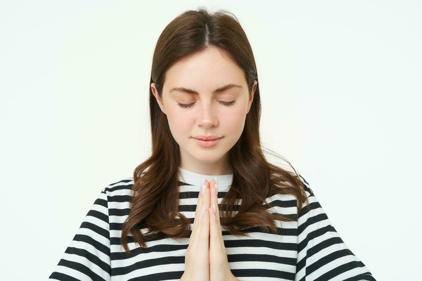 portret van vrouw tonen namaste gebaar, Holding palmen gebalde samen in de buurt borst, staand geïsoleerd over- wit achtergrond foto