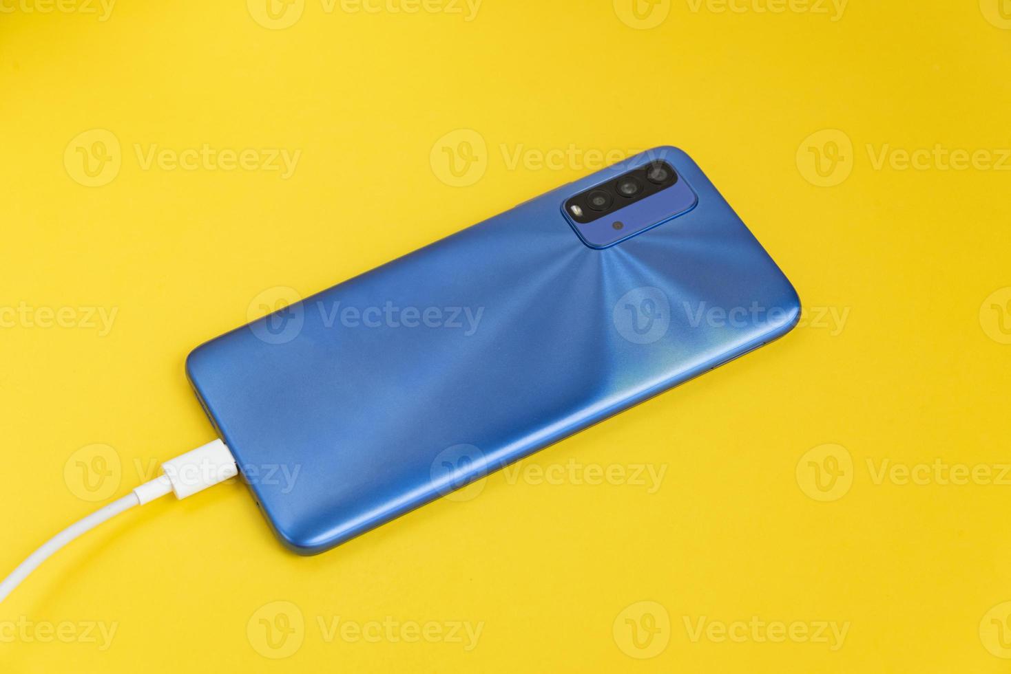 blauwe mobiele telefoon aangesloten op usb-kabeltype - opladen foto