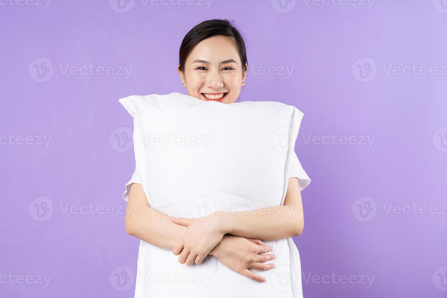 Aziatische vrouw met bovenste kussen, geïsoleerd op paarse achtergrond foto