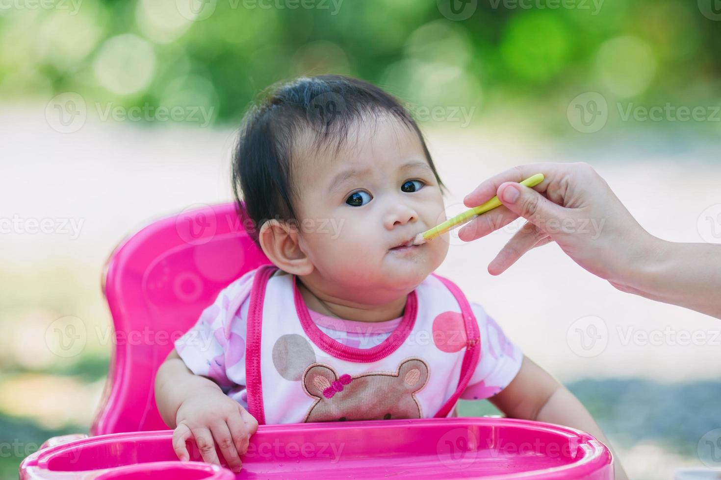 familieportret van moeder die haar baby van 7 maanden voedt. concept voor quality time van het dagelijks leven met eetactiviteit bij pasgeboren kind. foto