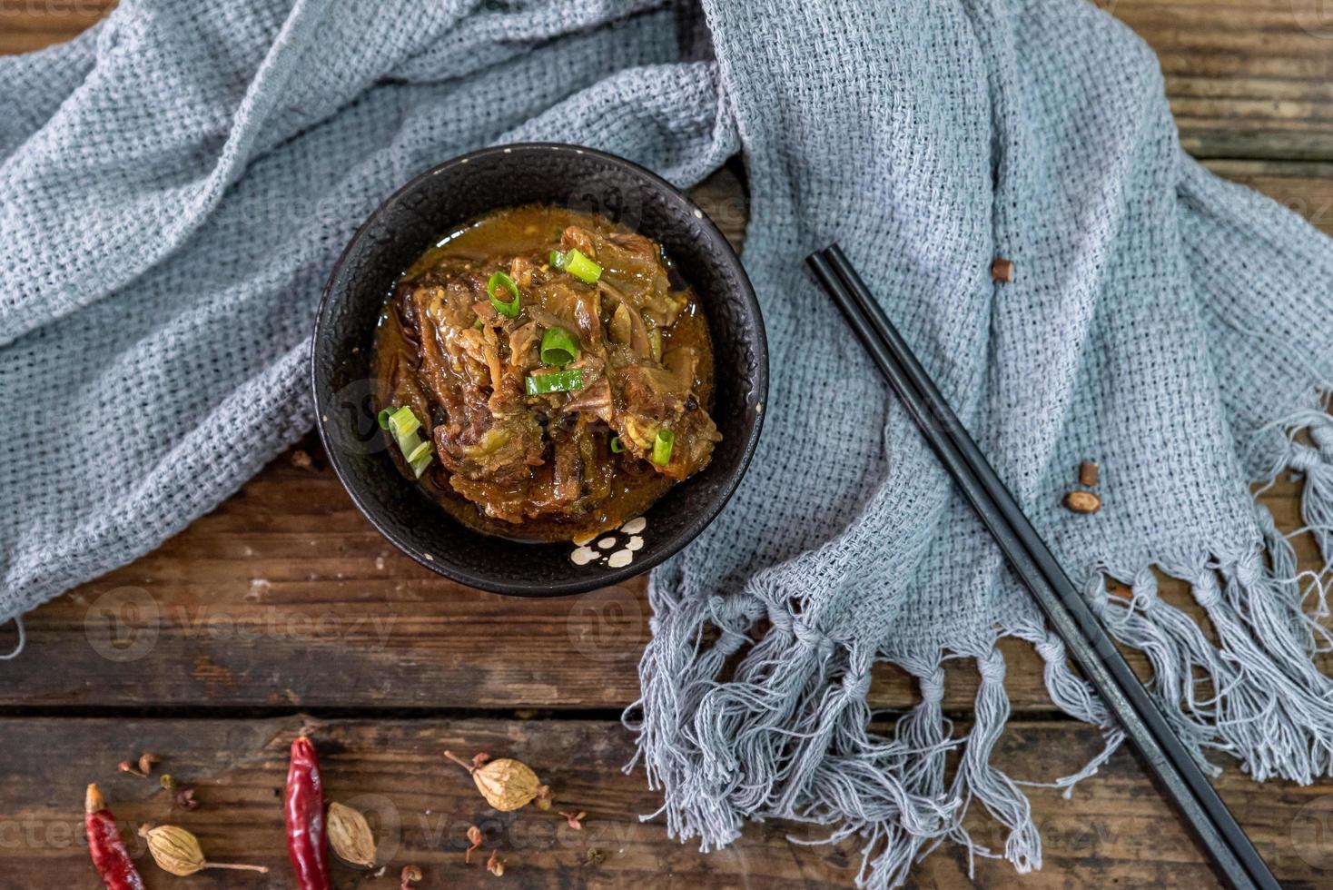 het eten van rundvlees zit in de kom op het kleed van de houten tafel foto