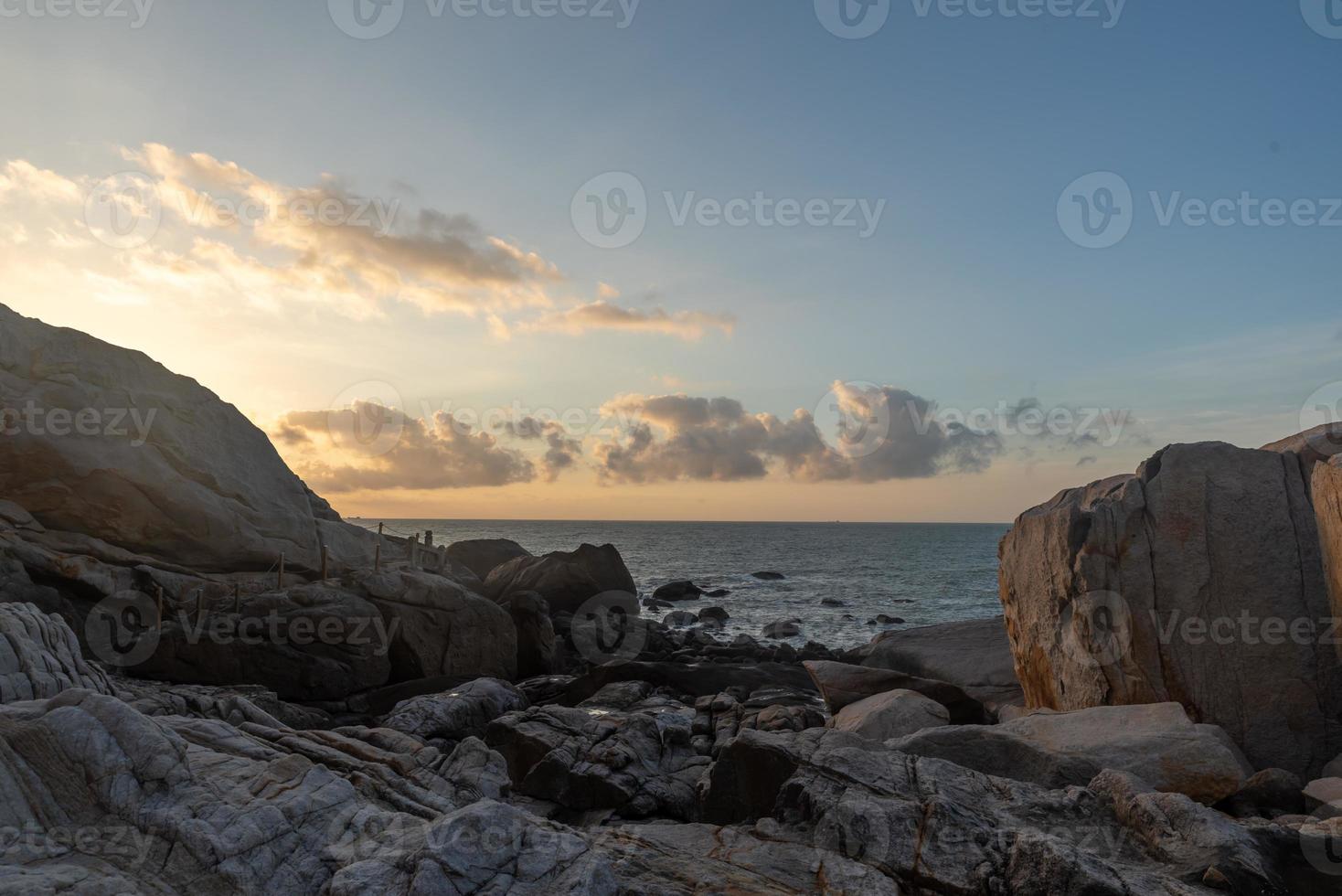 in de ochtend schijnt de zon op de rotsen en golven op het strand foto