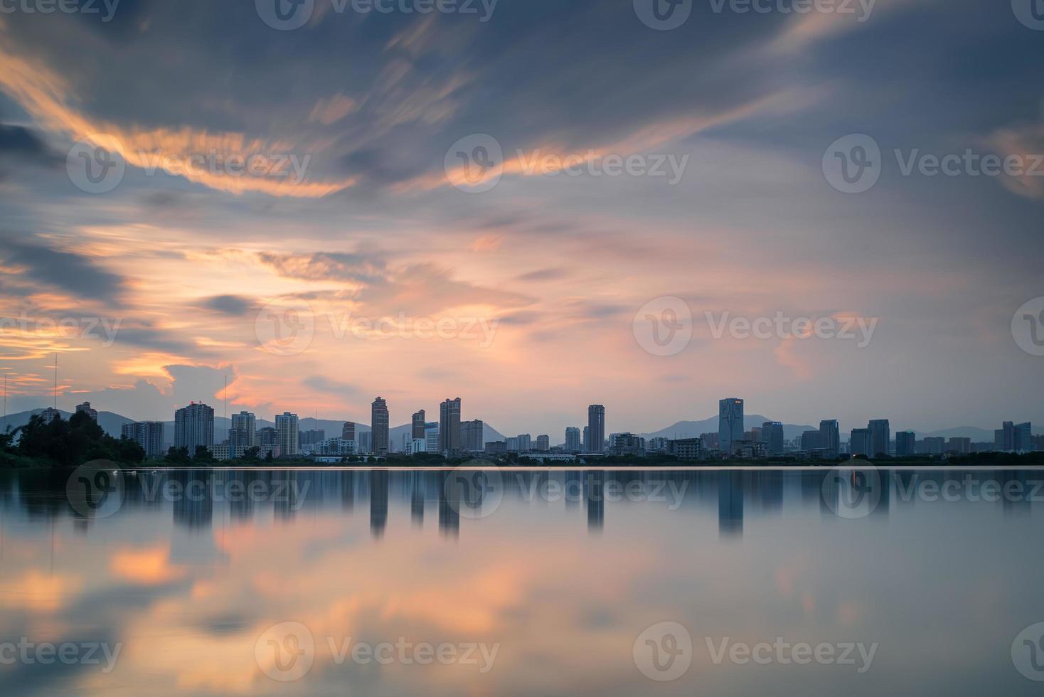 in de schemering weerspiegelt het meer het nachtelijke uitzicht op de stad foto