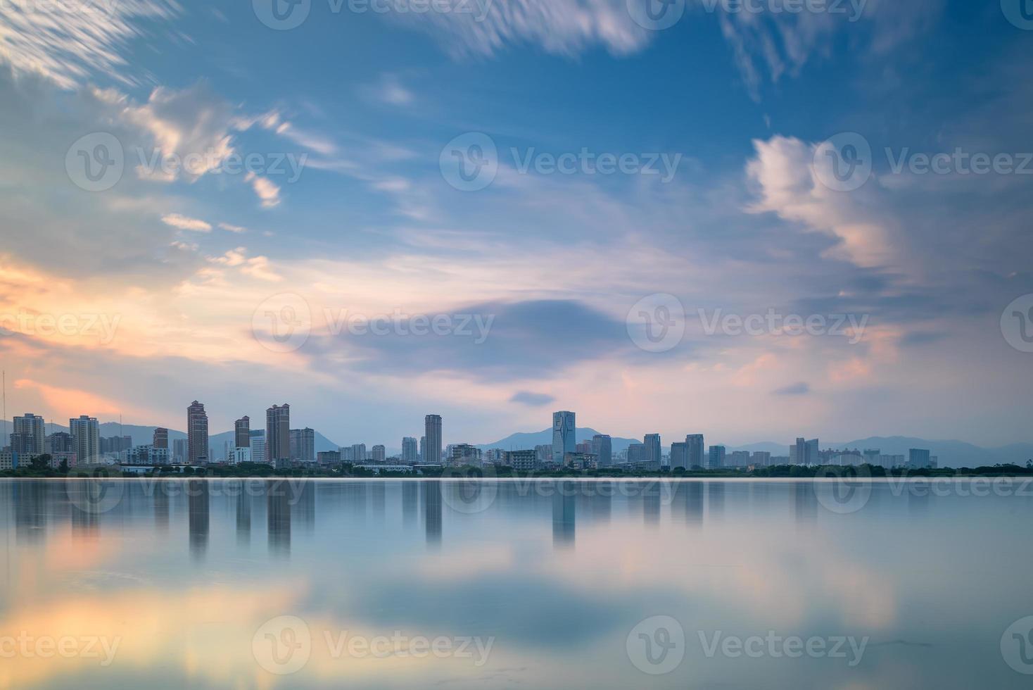 in de schemering weerspiegelt het meer het nachtelijke uitzicht op de stad foto