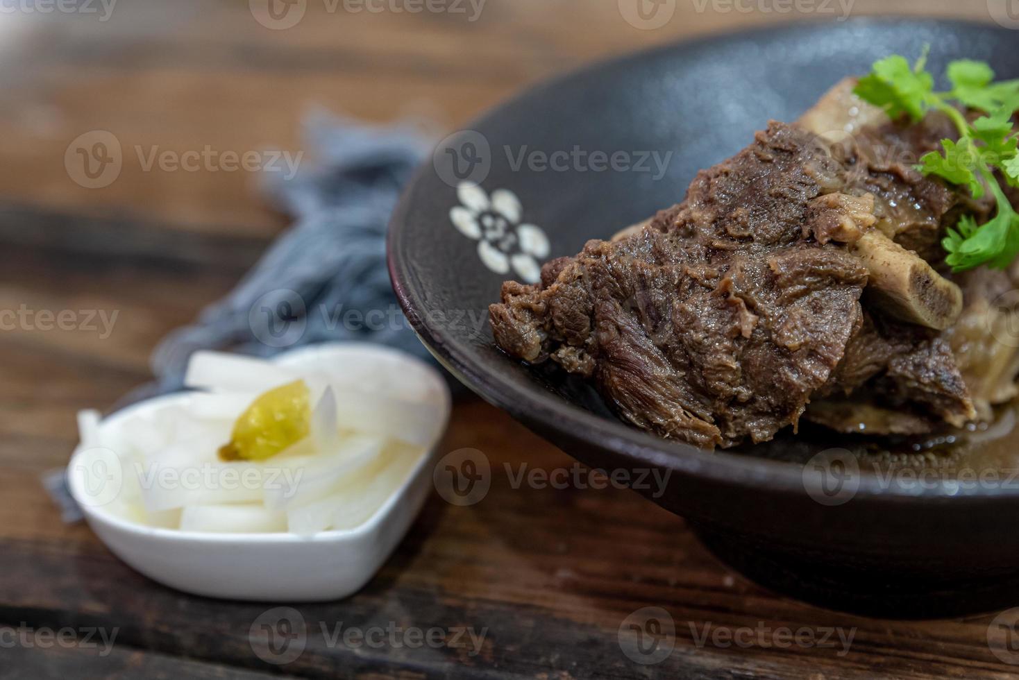 het eten van rundvlees zit in de kom op het kleed van de houten tafel foto