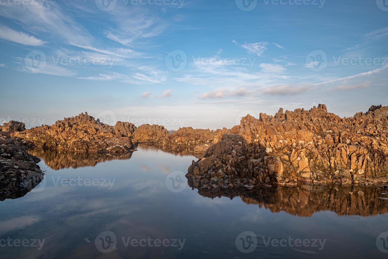 het zeewater tussen de kustriffen weerspiegelt de gele riffen en de blauwe lucht foto