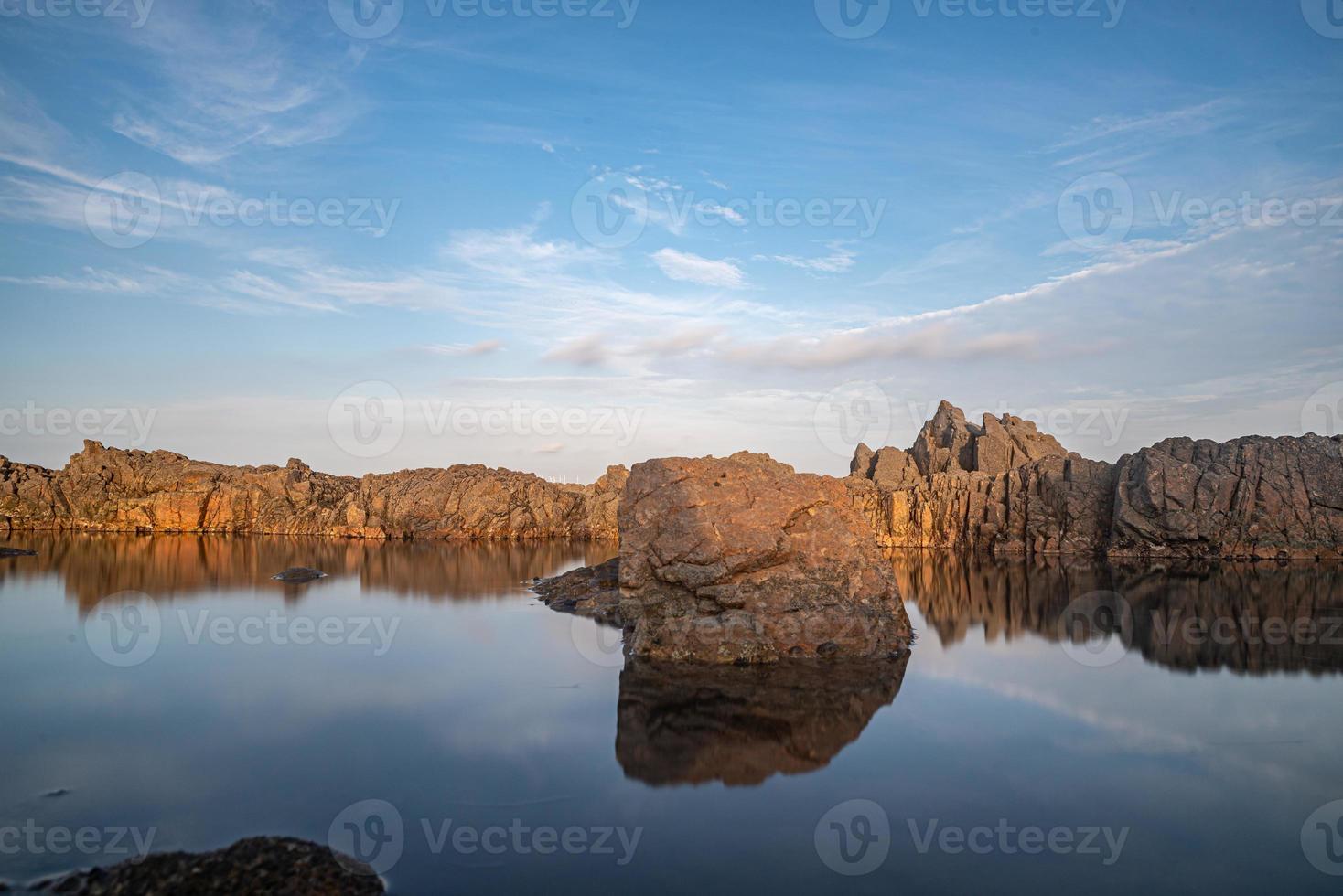 het zeewater tussen de kustriffen weerspiegelt de gele riffen en de blauwe lucht foto