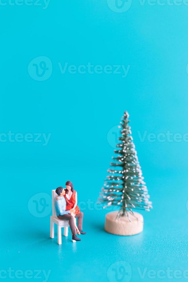 miniatuur mensen, verliefd stel naast een kerstboom foto