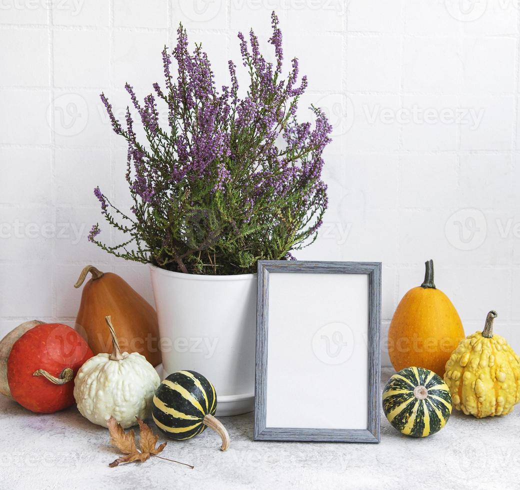 fotolijst en pompoen decor op tafel over witte tegel achtergrond. foto