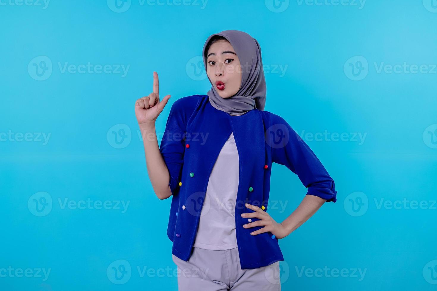 knappe charismatische jonge vrouw met het dragen van hijab wijzend geïsoleerd op lichtblauwe achtergrond foto