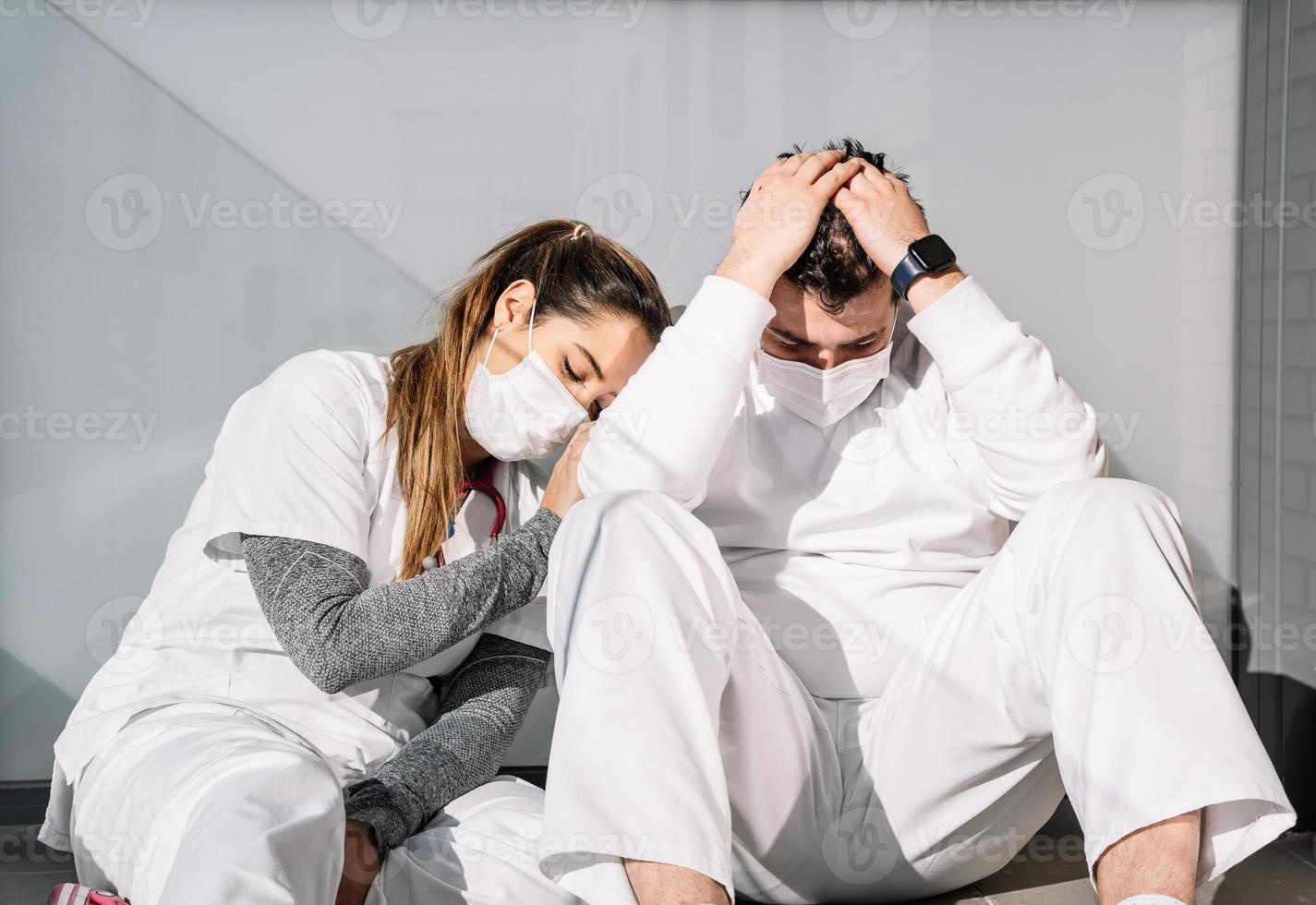 vermoeide medici slapen samen op de vloer op het terras van de kliniek foto