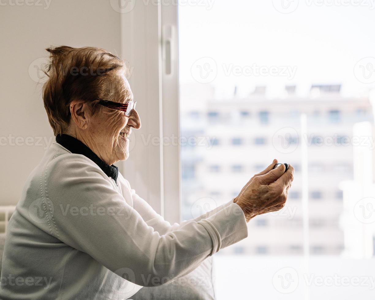 positieve oudere vrouw die thuis op videochat praat foto