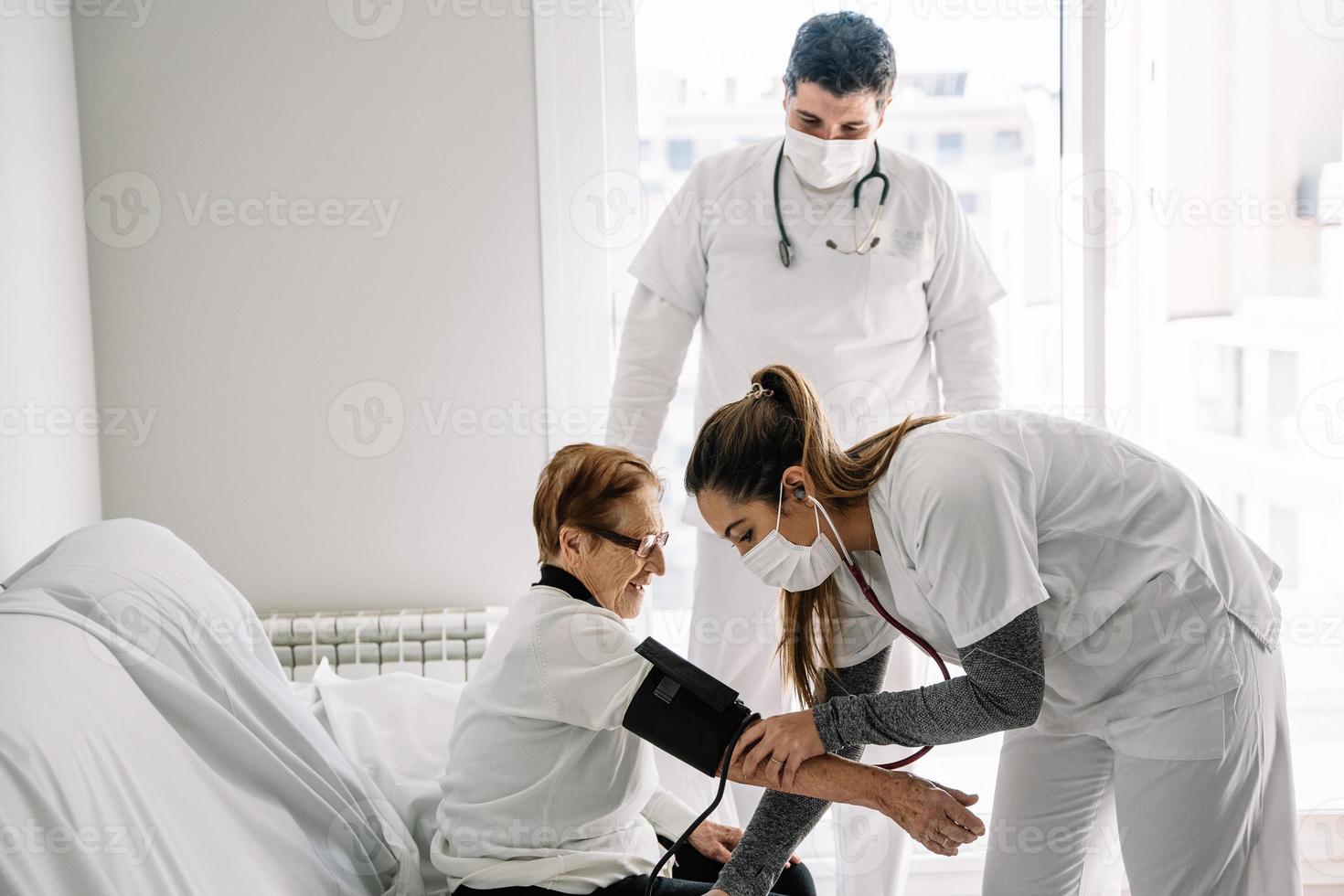 artsen die de bloeddruk van een oudere vrouw diagnosticeren foto