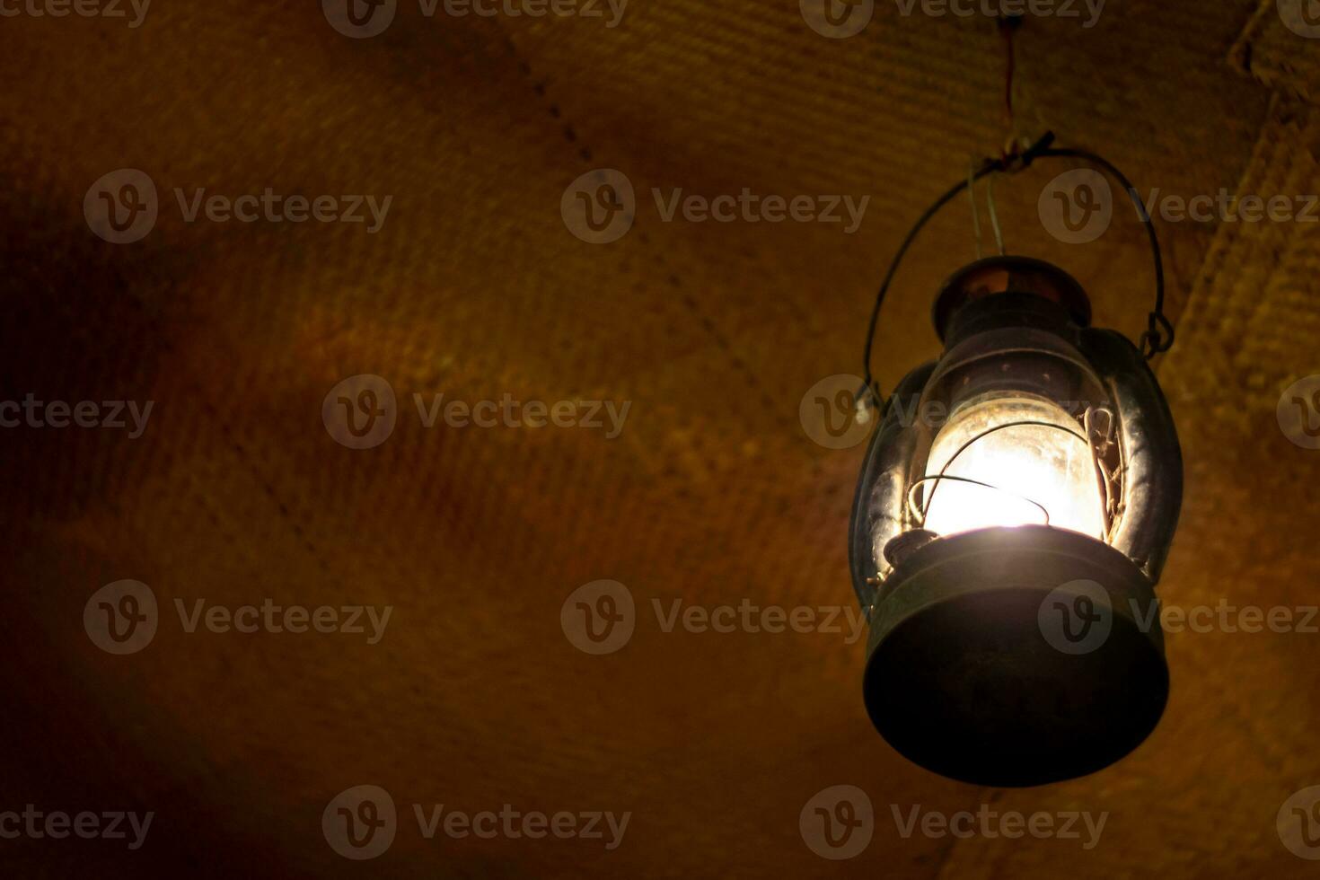 helder licht in een oude lantaarn hangende in een oud kamer foto