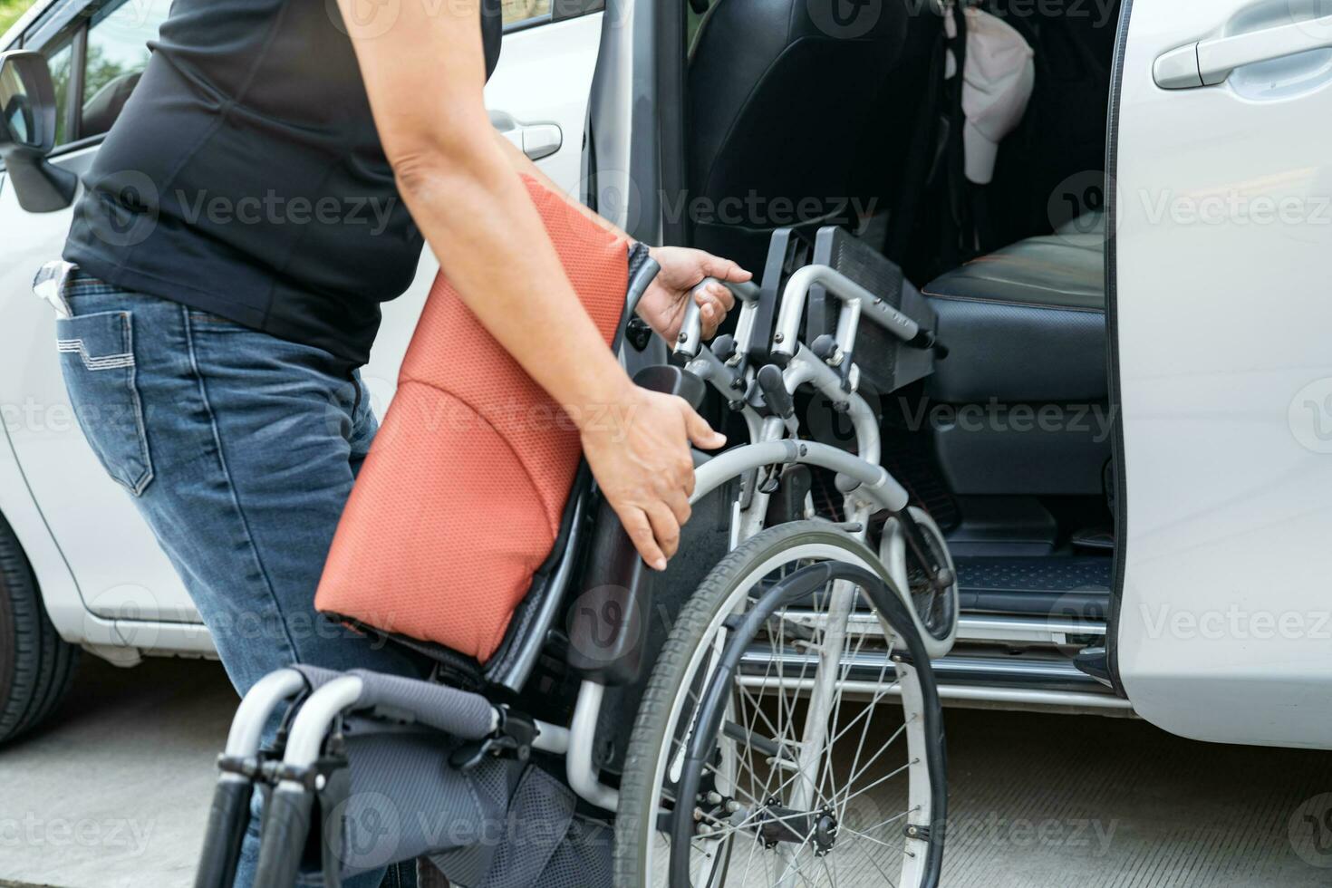 Aziatisch onbekwaamheid vrouw Aan rolstoel krijgen in haar auto, toegankelijkheid concept. foto