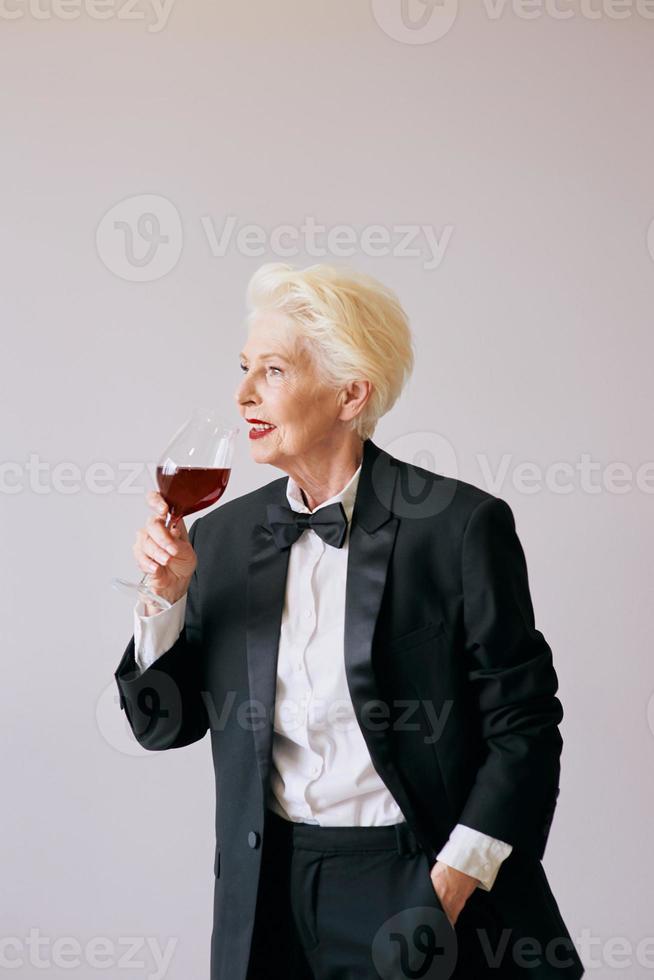 stijlvolle senior sommelier vrouw in smoking met glas of rode wijn. drank, volwassen, stijlconcept foto