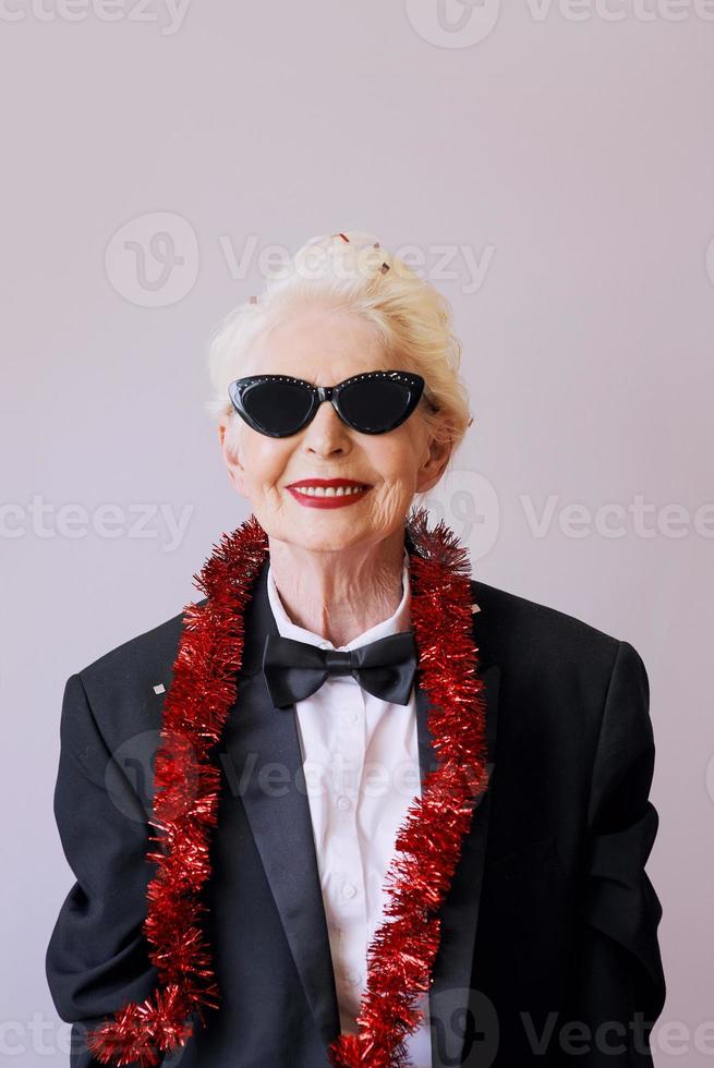 mooie stijlvolle volwassen senior vrouw in zonnebril en smoking Nieuwjaar vieren. plezier, feest, stijl, feestconcept foto