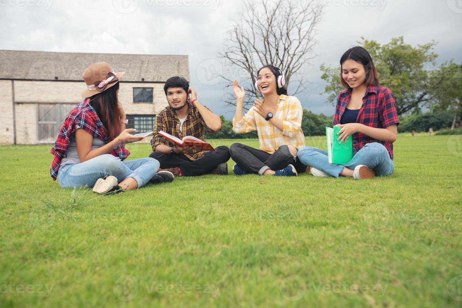 groep studenten lachen en plezier hebben het helpt ook om ideeën in het werk en project te delen. en bekijk ook het boek voor het examen buiten in de tuin. foto