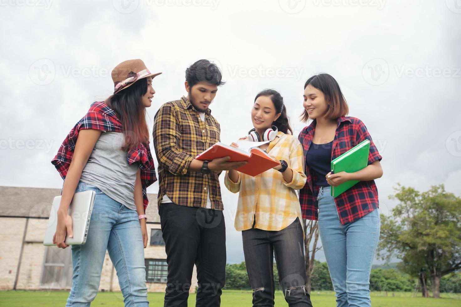 groep studenten lachen en plezier hebben het helpt ook om ideeën in het werk en project te delen. en bekijk ook het boek voor het examen buiten in de tuin. foto