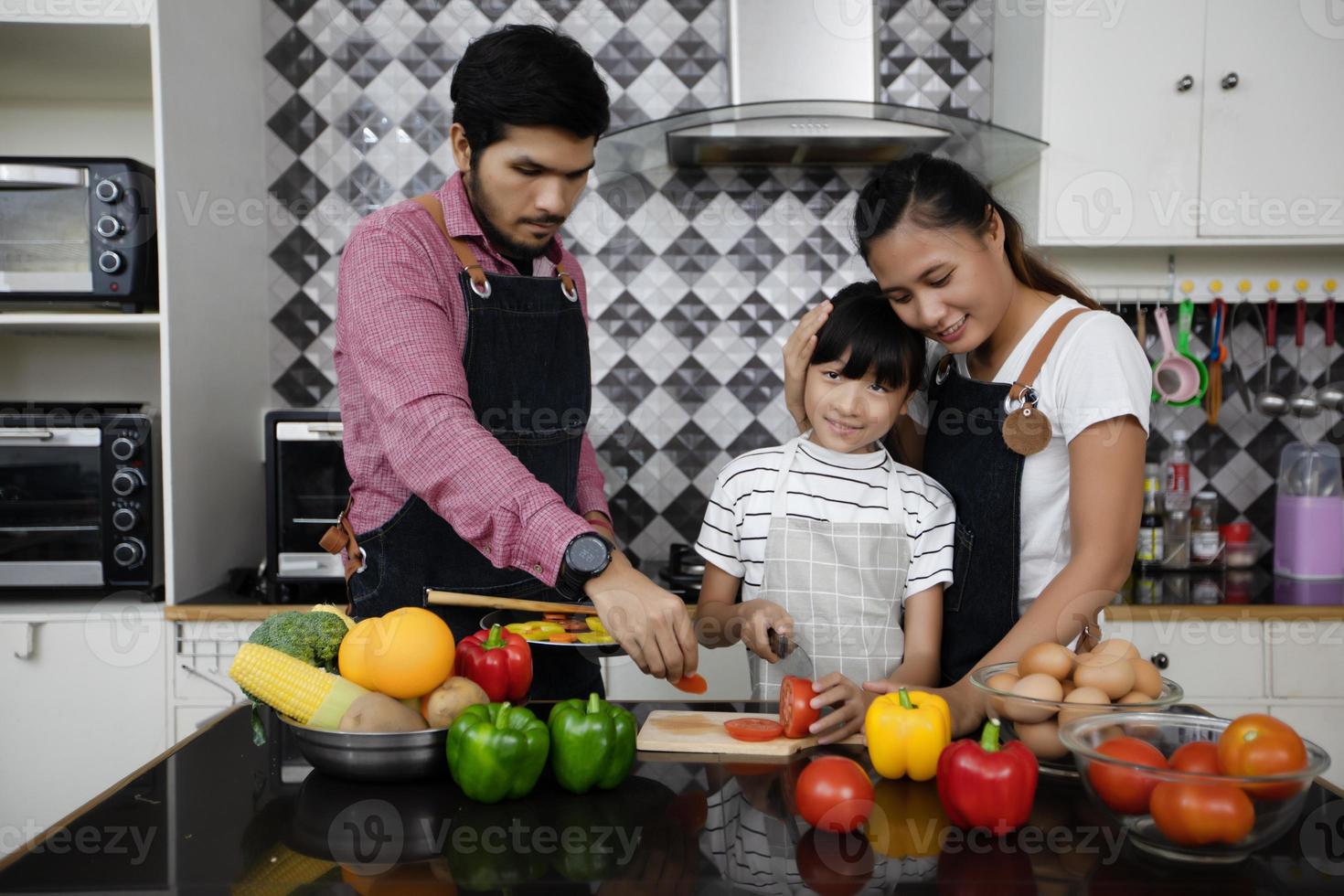 gelukkige familie laat vader, moeder en hun dochtertje samen koken in de keuken foto