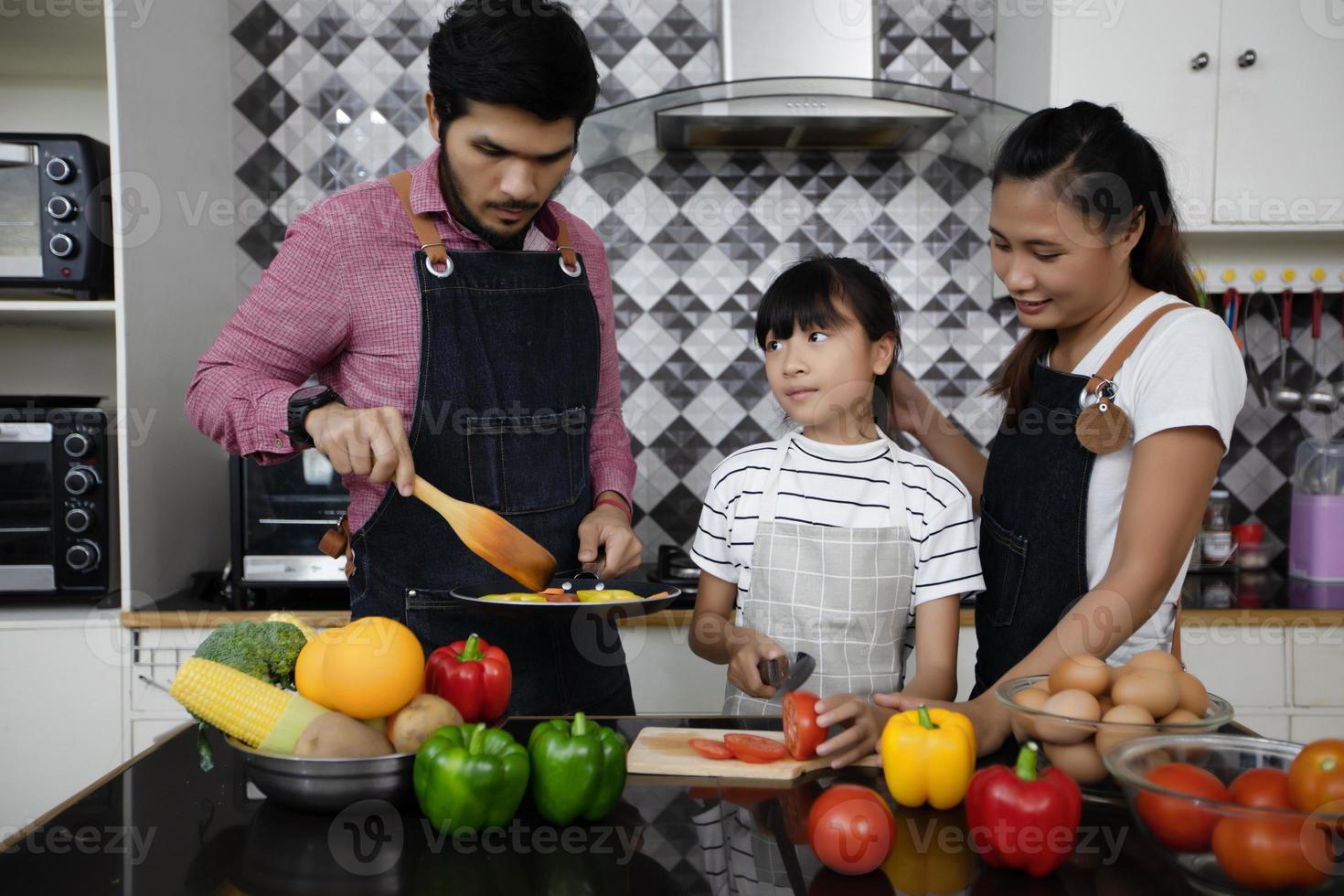 gelukkige familie laat vader, moeder en hun dochtertje samen koken in de keuken foto