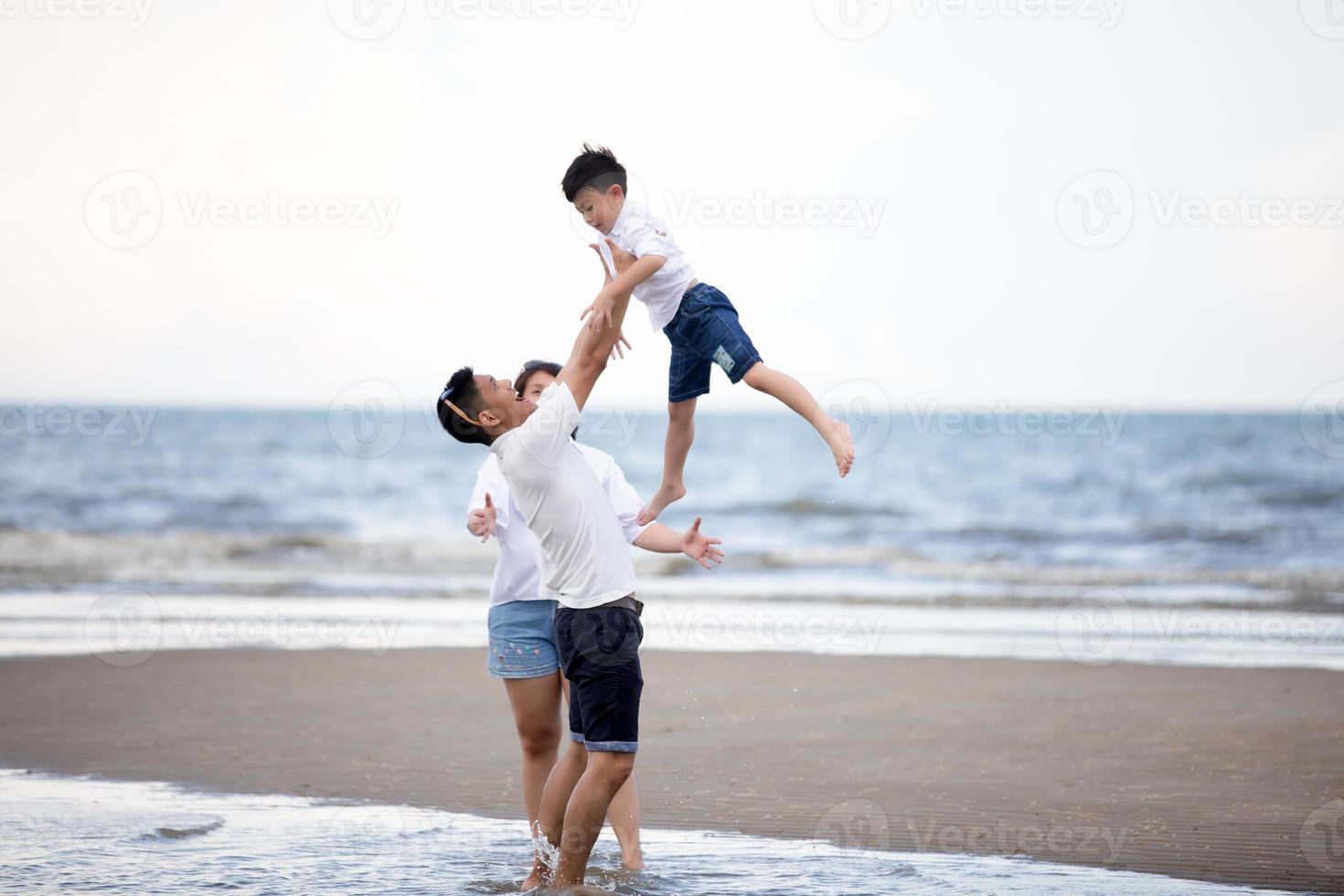 actieve ouders en mensen buitenactiviteit op zomervakanties en vakantie met kinderen. Gelukkige familie en zoon lopen met plezier van zonsondergang zee op zandstrand. foto