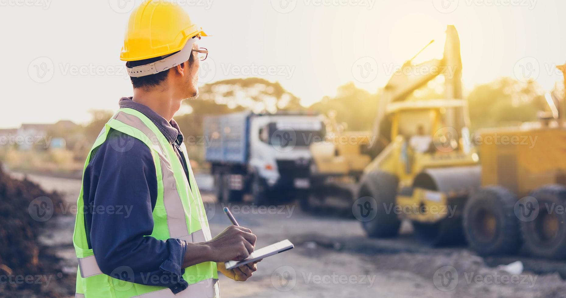 Aziatische ingenieur met veiligheidshelm met behulp van tablet pc-computer inspecteren en werken op de bouwplaats foto